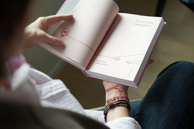 A hand holding open the endpapers, which continue the cover’s line illustration