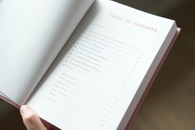 A hand holding the book open to the table of contents